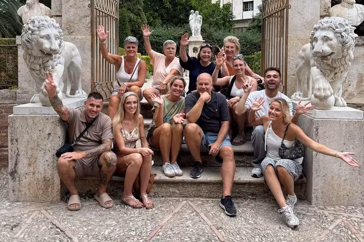 Happy Valencia Ruzafa guided bike tour group posing by stone lion statues at a historic garden gate
