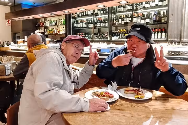 Travelers tasting Spanish tapas at a Valencia wine bar during a guided gourmet tapas tour by bike or on foot