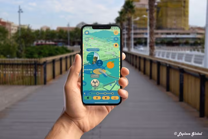 Hand holding smartphone displaying Valencia self-guided walking tour app with interactive map on scenic bridge