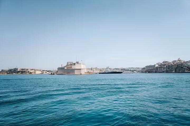 Valletta harbor with historic Fort St Angelo and city skyline viewed from turquoise Mediterranean Sea
