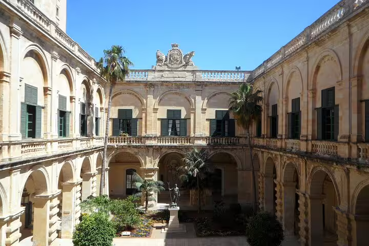 Historic Valletta courtyard with arched cloisters and palms, visited on a half-day Valletta tour with a local