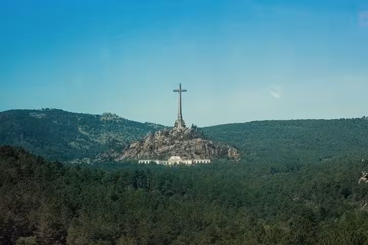 Panoramic view of the Valley of the Fallen monument surrounded by lush greenery near Madrid, Spain.