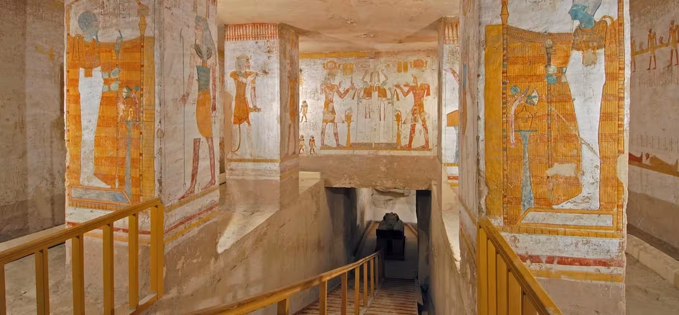 Colorful ancient Egyptian hieroglyphic murals lining the painted walls and stairway inside a Valley of the Kings tomb