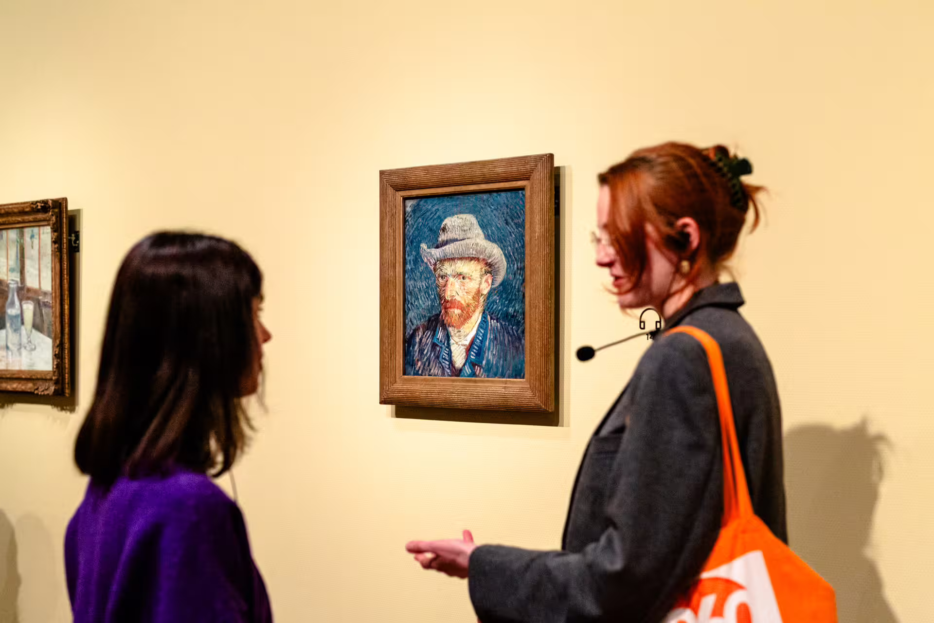 Visitors engage with a guide during a Van Gogh painting tour, highlighting an iconic self-portrait for an immersive art experience.
