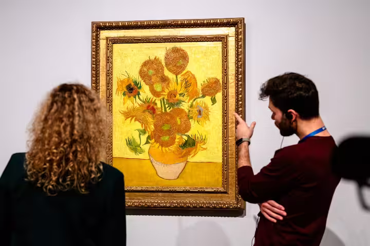 Visitors admire Van Gogh's famous "Sunflowers" painting during an engaging guided tour at the art museum.