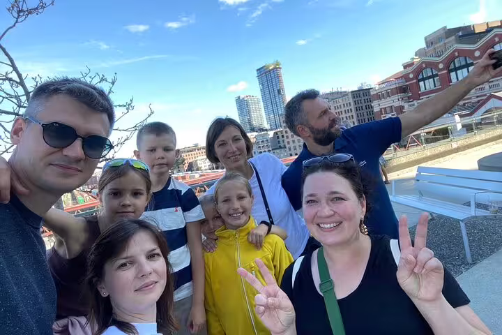Family group selfie in Vancouver Gastown during scavenger hunt tour with skyline and historic buildings behind