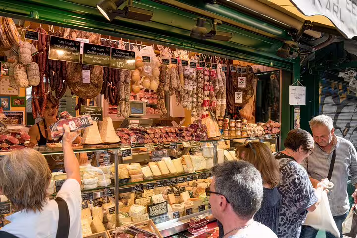 Visitors explore a vibrant Italian deli at the Vatican Market, showcasing an array of cheeses and cured meats during a tasting tour.