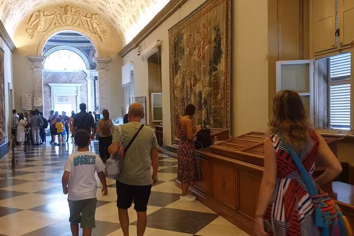 Visitors explore ornate hallways adorned with tapestries during the Fast Track Guided Tour Vatican Museum experience.