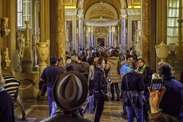 Crowds of tourists explore ornate marble halls of the Vatican Museums on a fast track entrance guided group tour in Rome