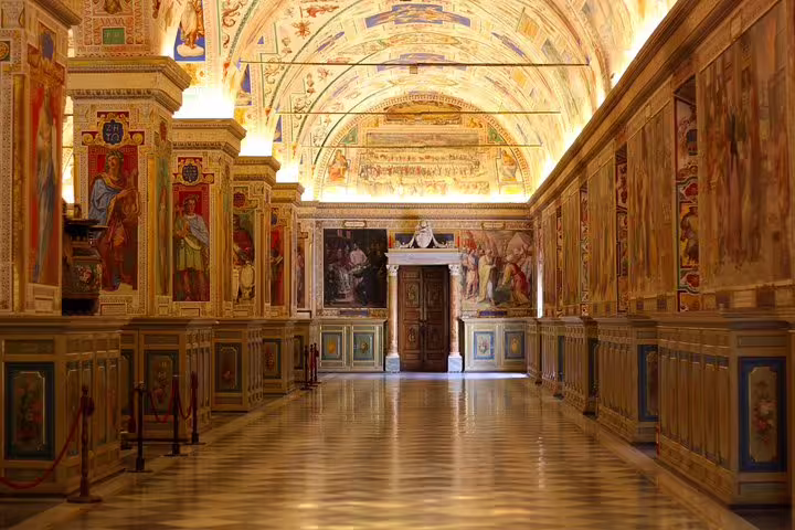 Ornate gallery of the Vatican Museums with illuminated vaulted ceilings and frescoed walls on a fast track guided tour