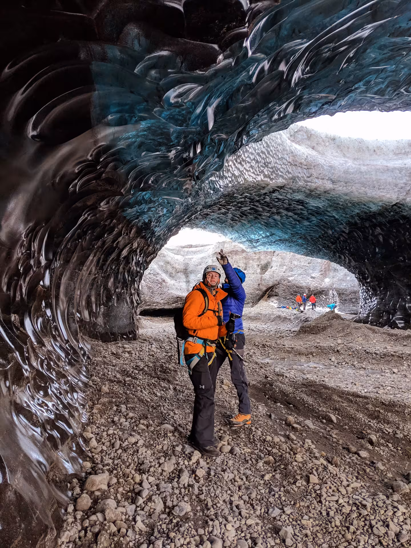 Two explorers in climbing gear inside a stunning blue ice cave at Vatnajokull glacier, Iceland
