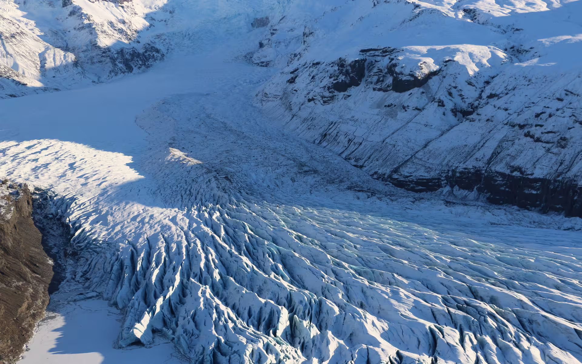 Aerial view of Vatnajokull glacier with deep blue crevasses and snow-covered mountains in Iceland