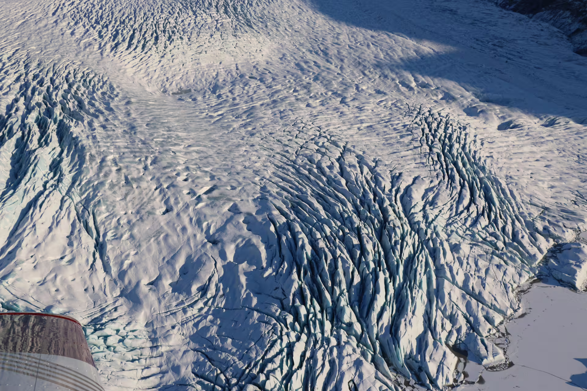 Aerial view of Vatnajokull glacier crevasses and ice formations from airplane window, Iceland