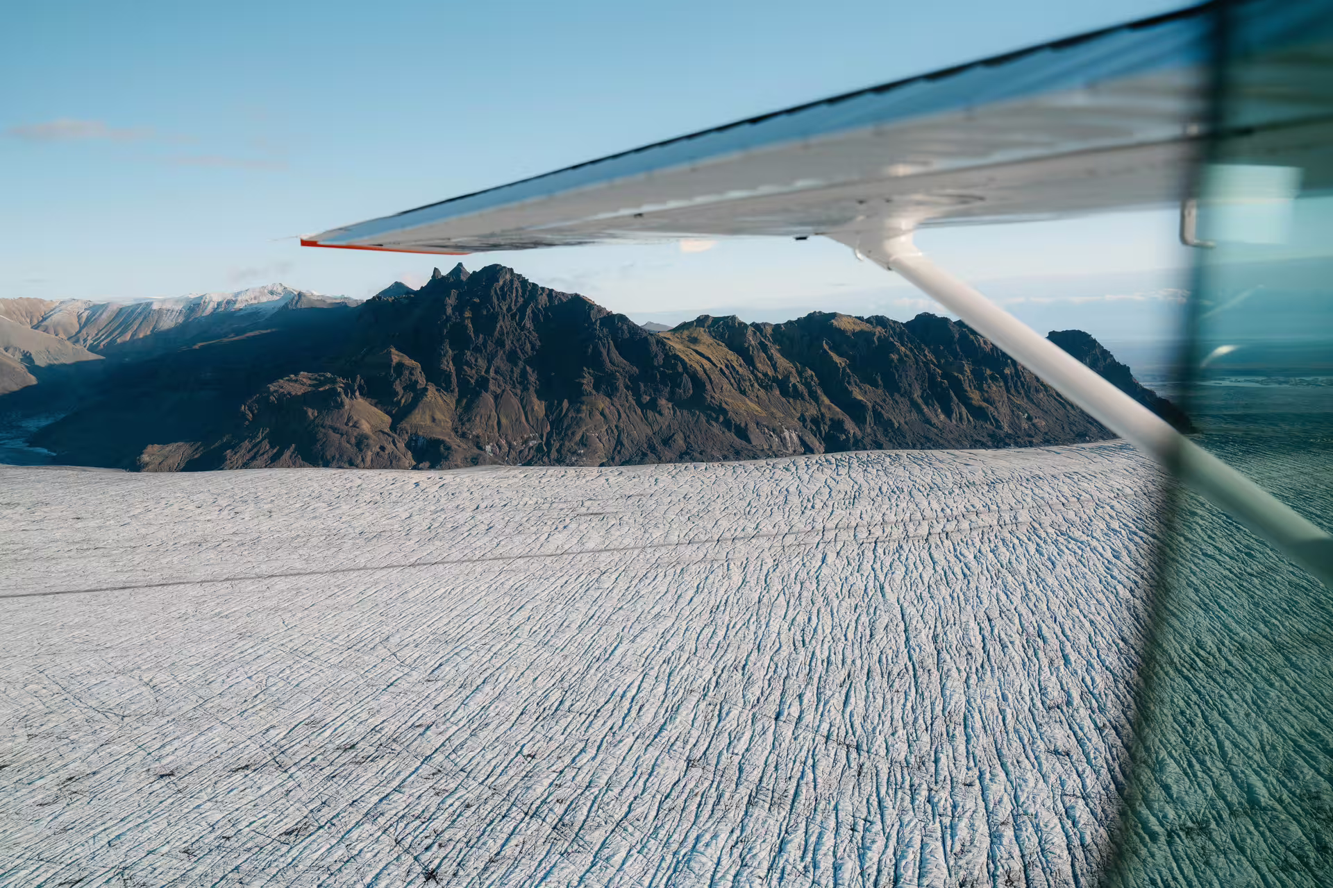Aerial view of Vatnajokull glacier and rugged mountains from small airplane window, Iceland