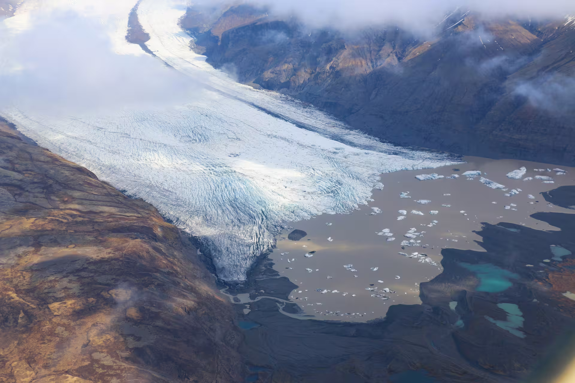 Aerial view of Vatnajokull glacier flowing into a glacial lagoon with floating icebergs, Iceland