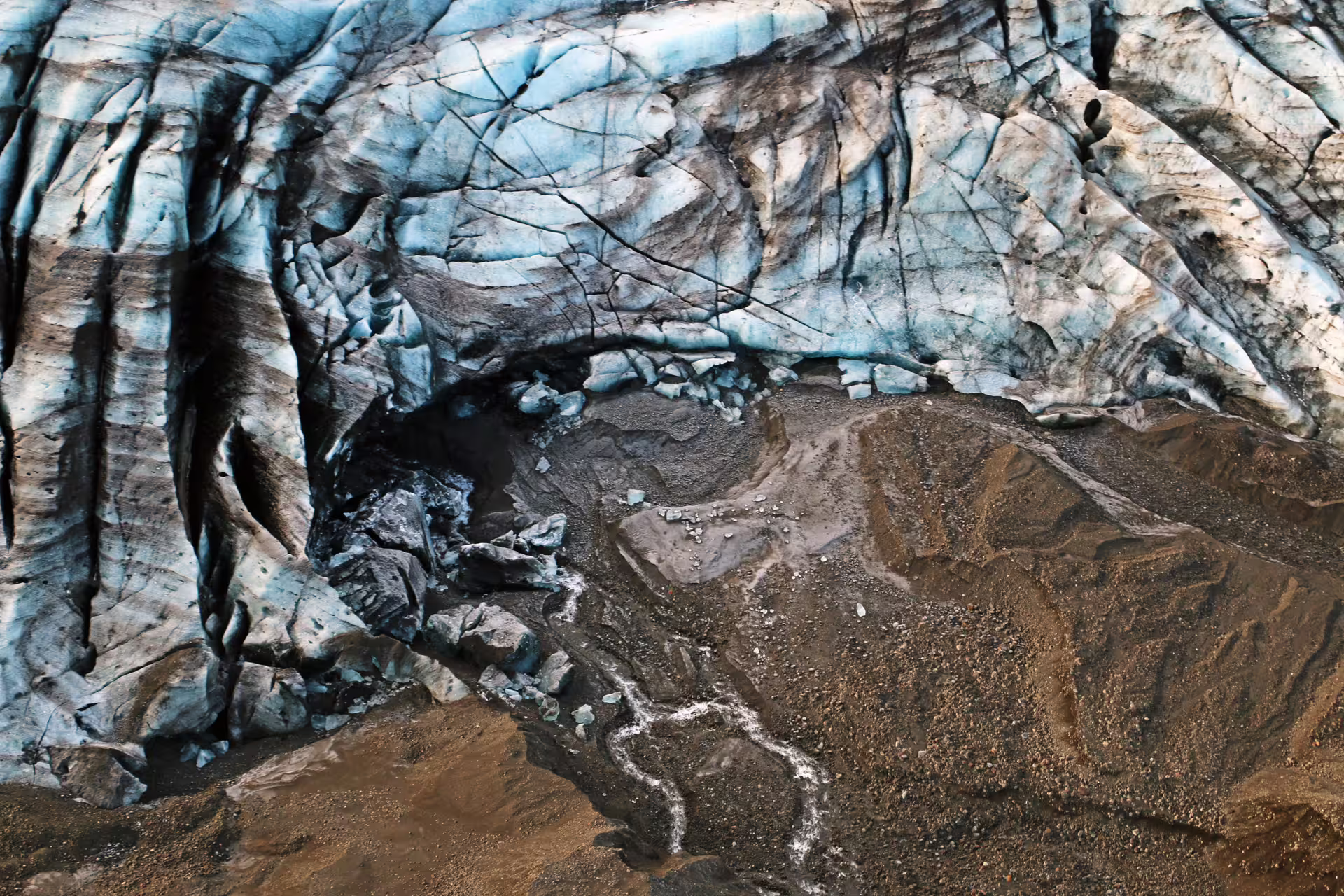 Aerial view of Vatnajokull glacier ice face with blue crevasses and dark volcanic sediment below