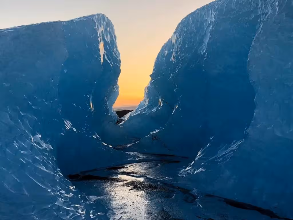 Narrow passage between two blue ice walls on Vatnajokull glacier at golden sunset