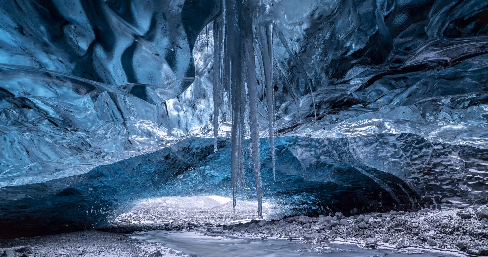 Interior of Vatnajokull glacier ice cave with blue ice walls and icicles hanging from ceiling, Iceland