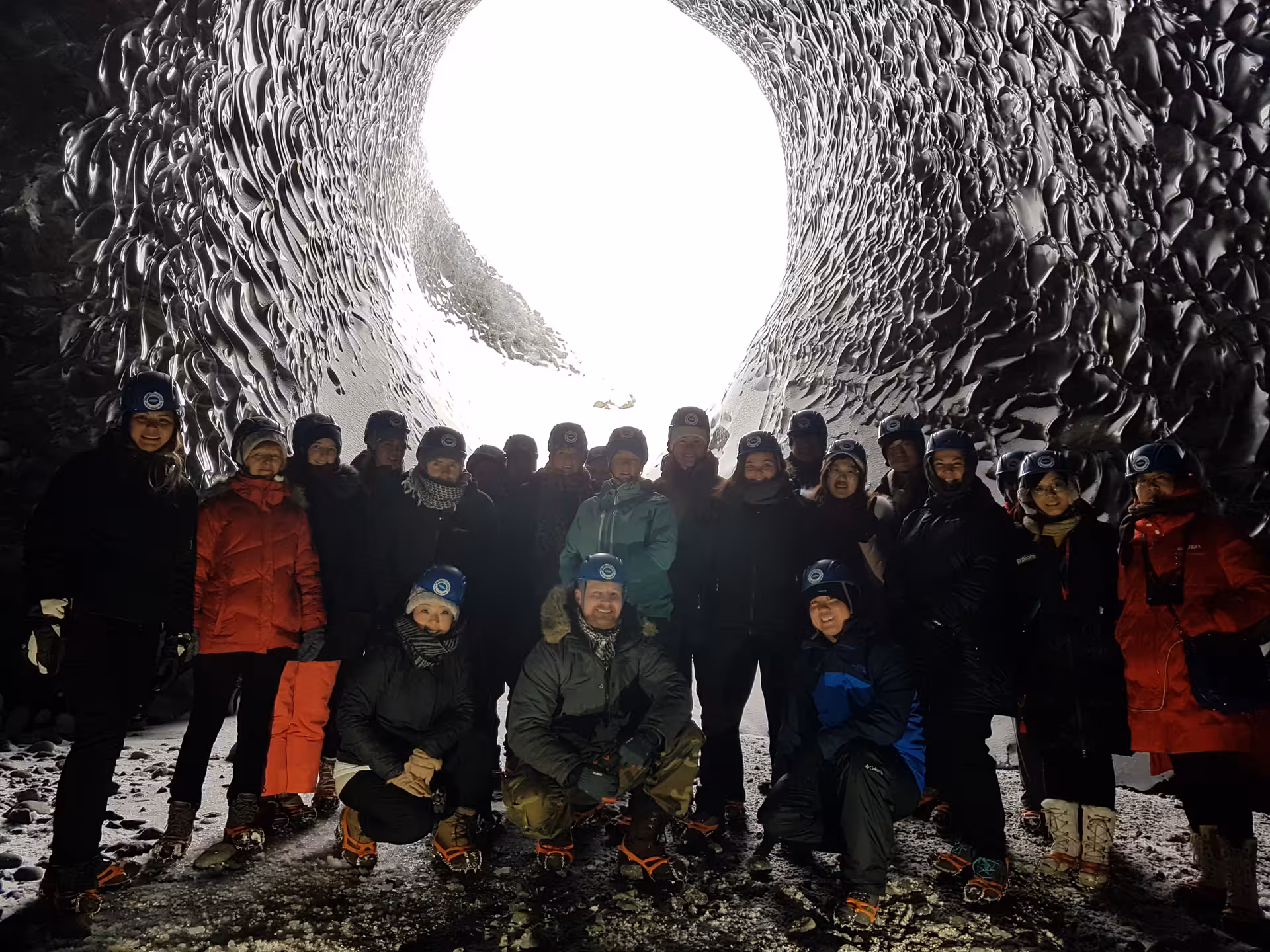 Tour group inside Vatnajokull glacier ice cave wearing helmets and crampons, Iceland