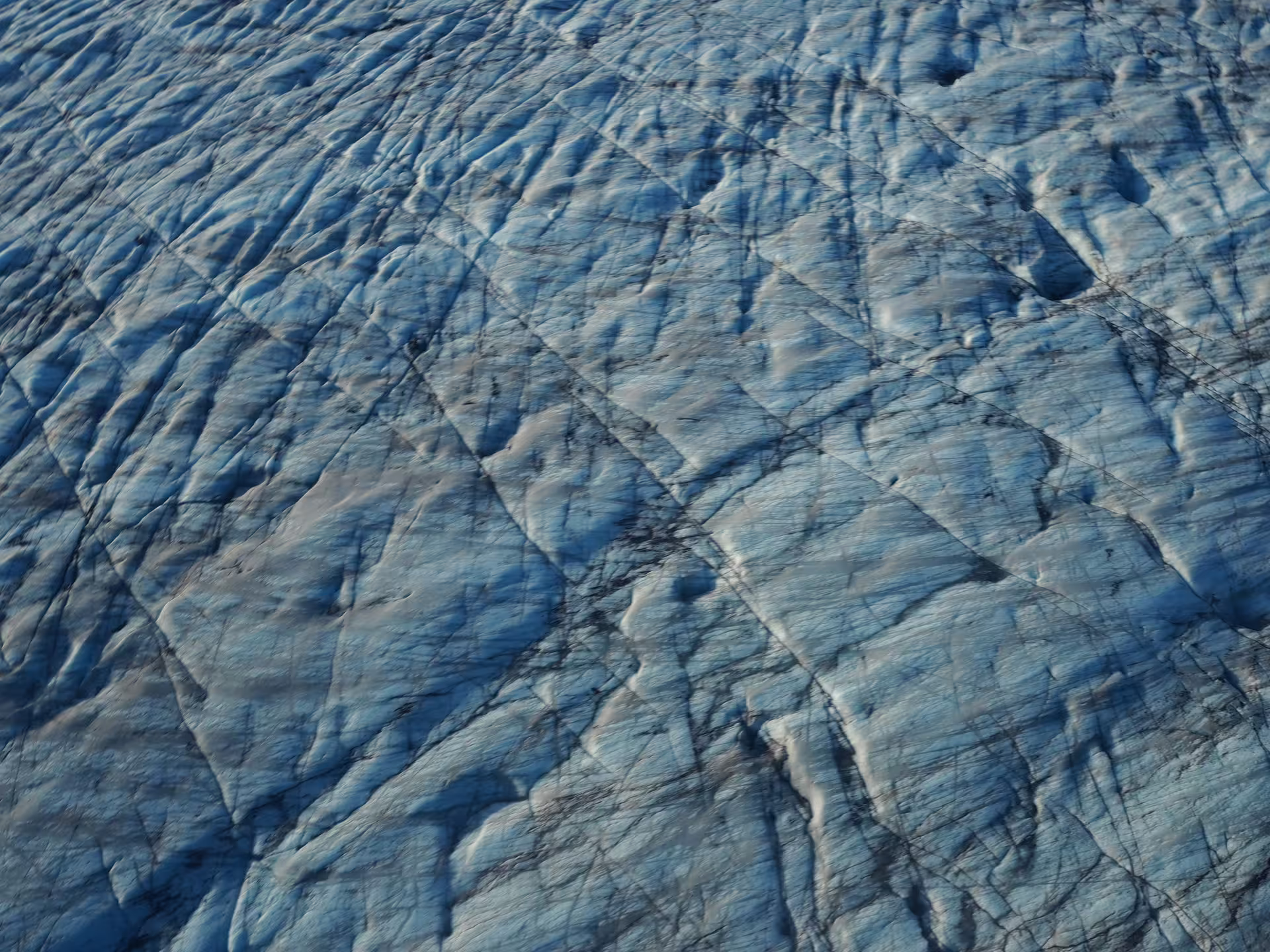 Aerial view of blue glacial ice surface with dark crevasse lines on Vatnajokull glacier Iceland