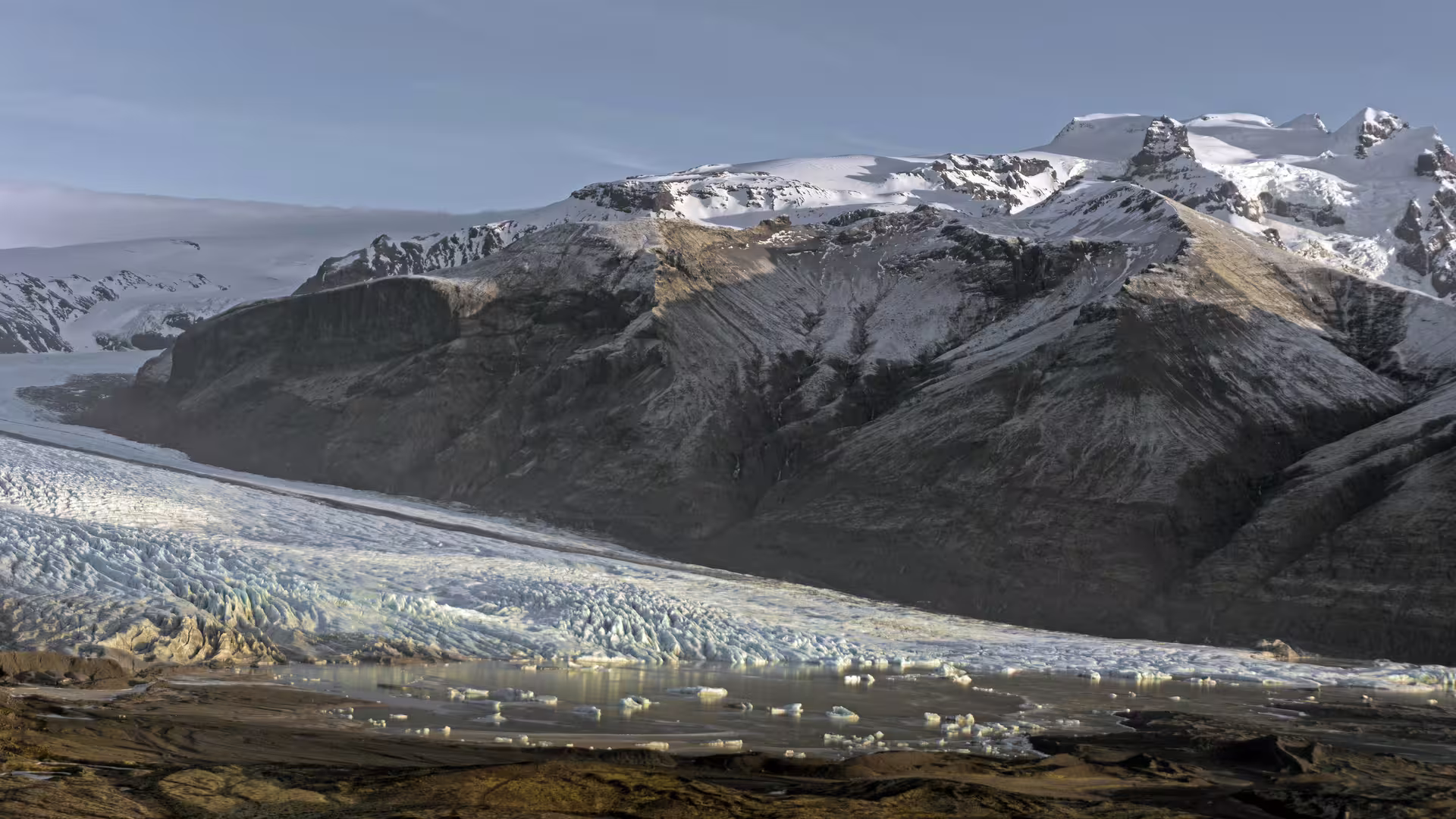 Vatnajokull glacier flowing into a glacial lagoon with snow-capped mountains in Skaftafell, Iceland