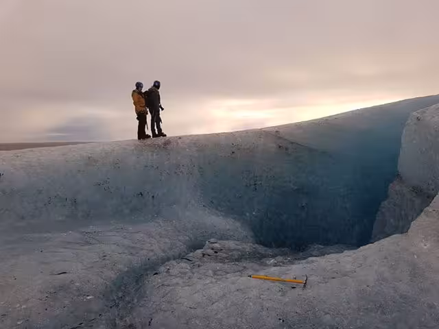 Two hikers standing on the edge of a glacier crevasse on Vatnajokull glacier, Iceland
