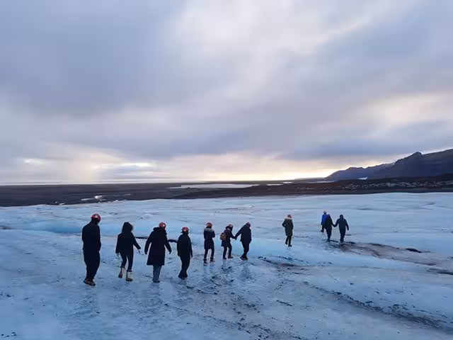 Group of tourists walking in a line across Vatnajokull glacier in Iceland under cloudy sky