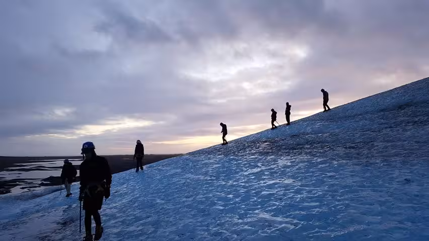 Group of hikers climbing Vatnajokull glacier at sunset near Jokulsarlon, Iceland