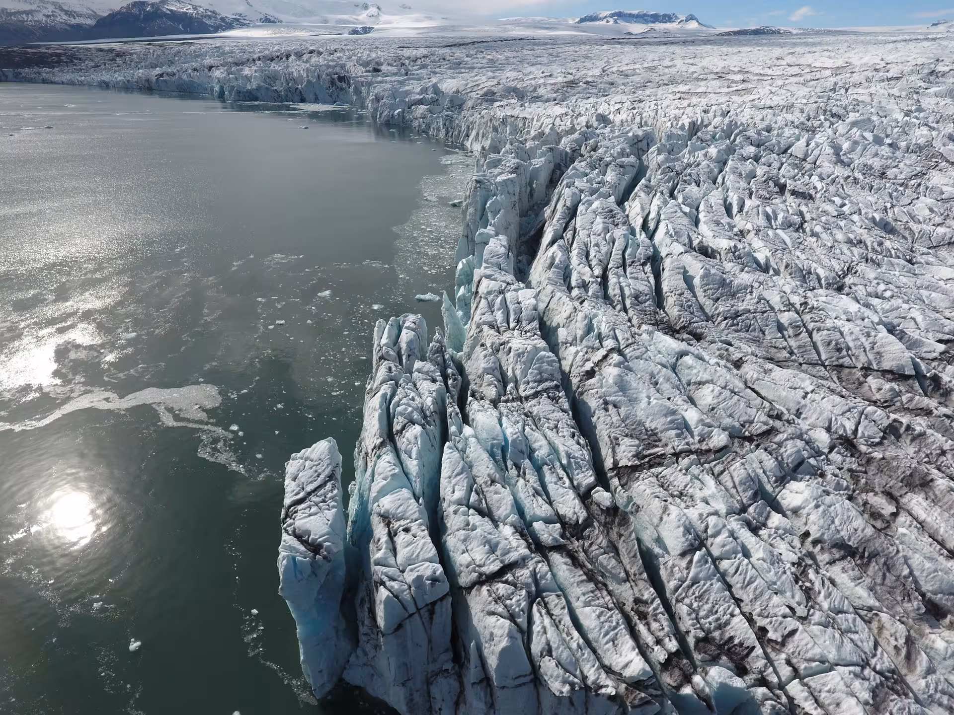 Aerial view of Vatnajokull glacier edge meeting glacial lagoon with jagged ice formations in Iceland