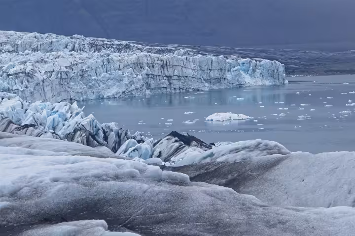 Vatnajokull glacier face with floating icebergs in glacial lagoon, Iceland