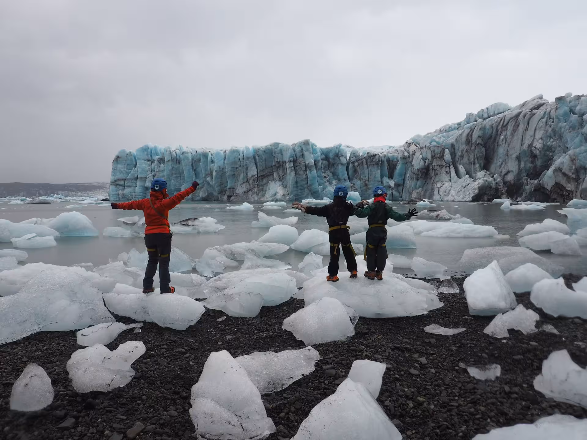Three guides posing on icebergs at Jokulsarlon glacier lagoon with Vatnajokull glacier in background