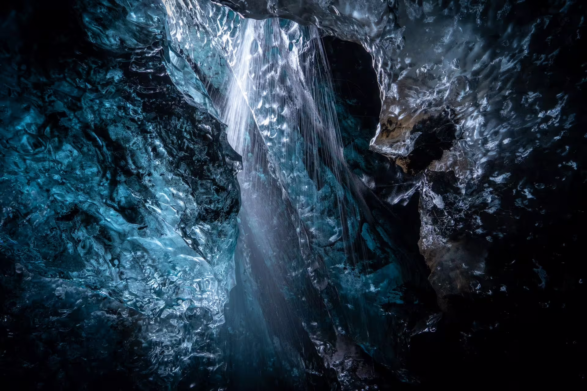 Glowing blue ice cave interior with cascading meltwater stream inside Vatnajokull glacier Iceland