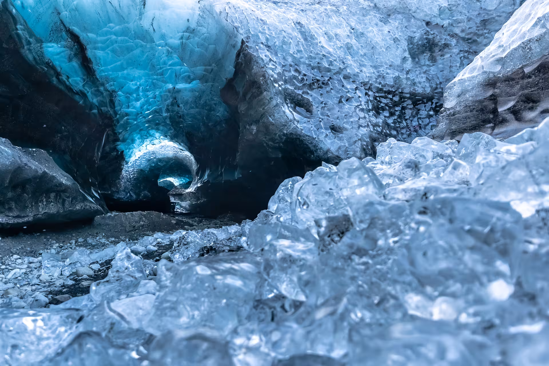 Blue glacial ice cave tunnel with scattered ice chunks at Vatnajokull glacier, Iceland