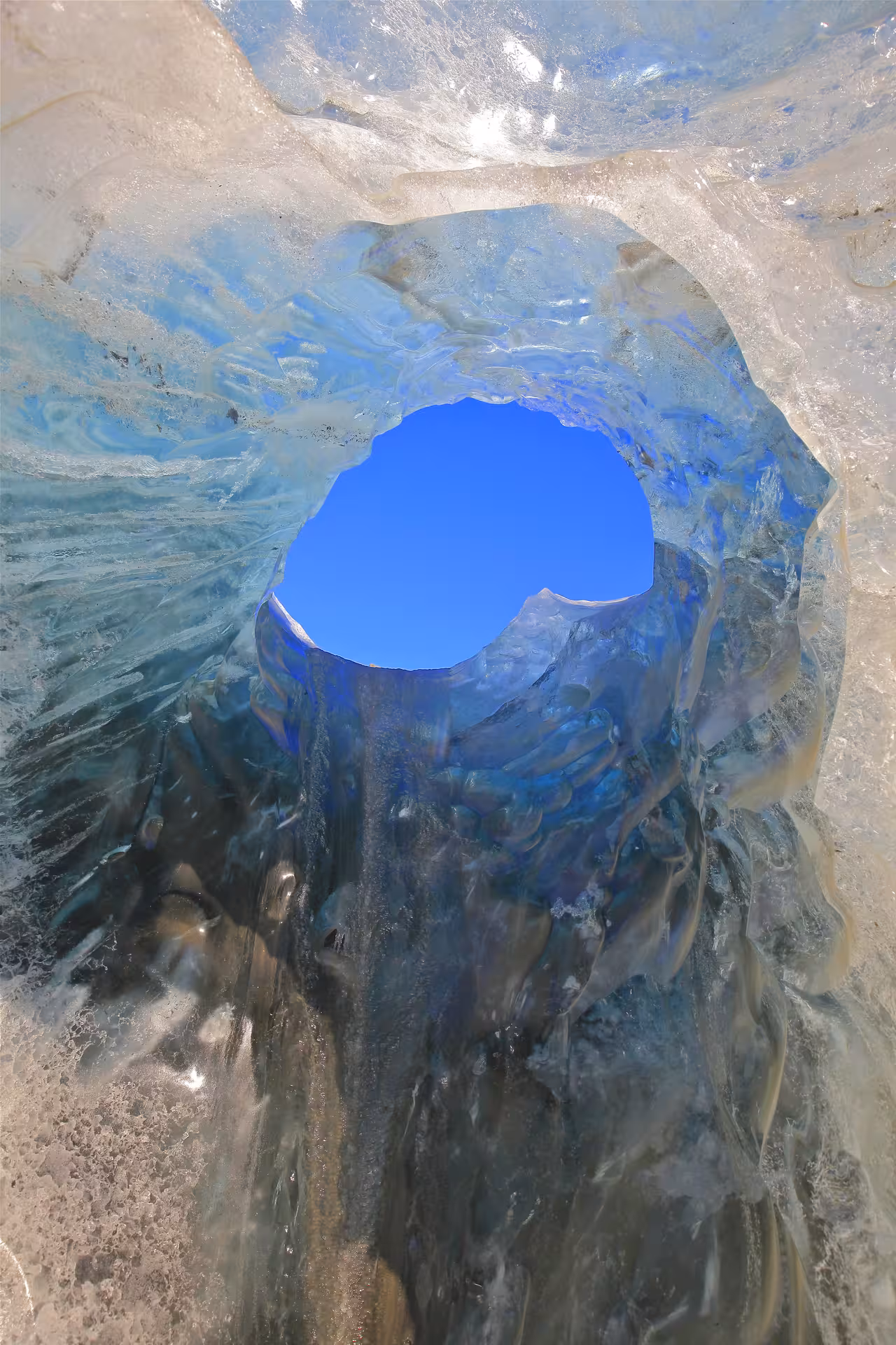 View through a glacial ice cave opening revealing blue sky at Vatnajokull glacier Iceland