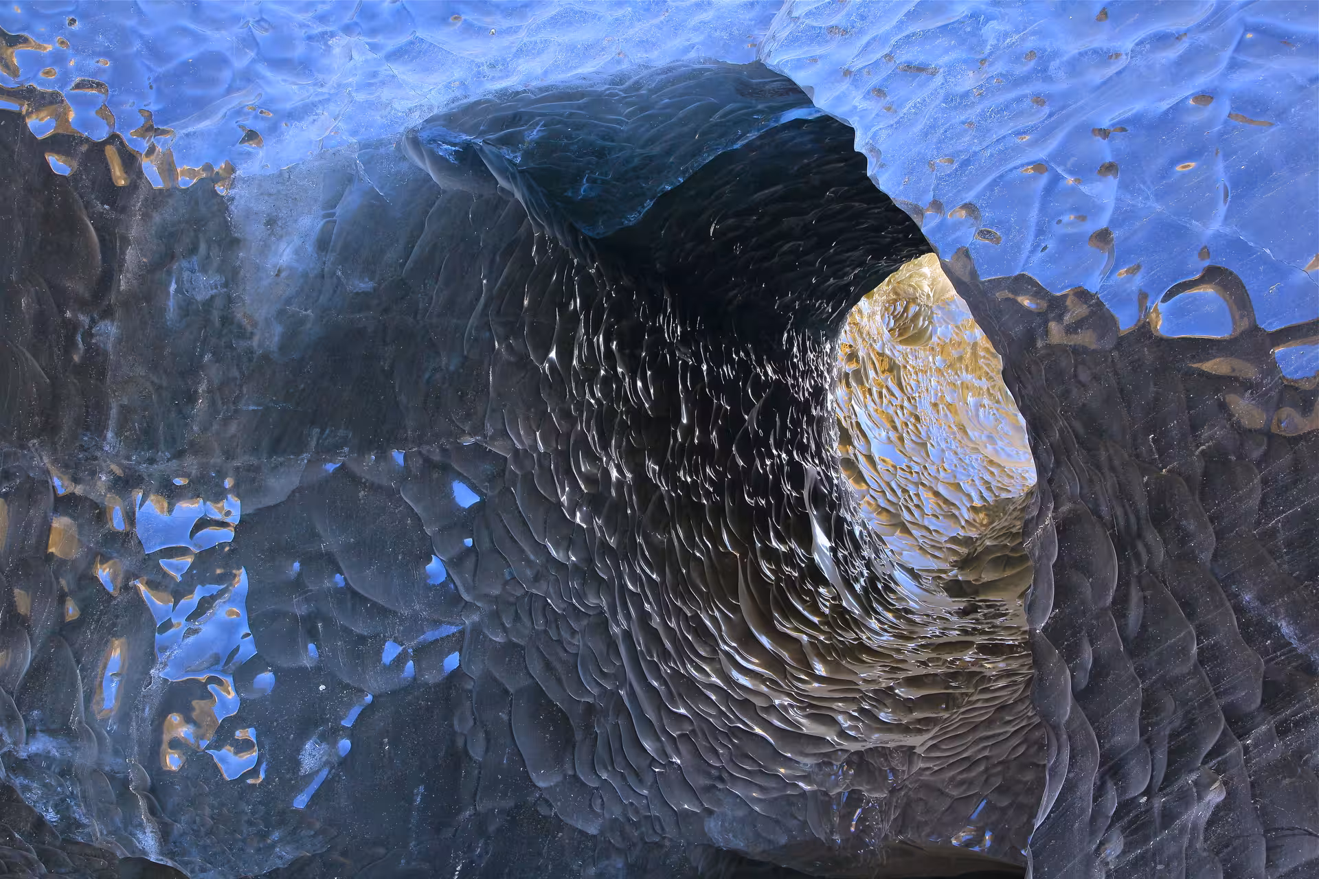Interior of a glacial ice cave tunnel at Vatnajokull with blue ice and textured dark walls