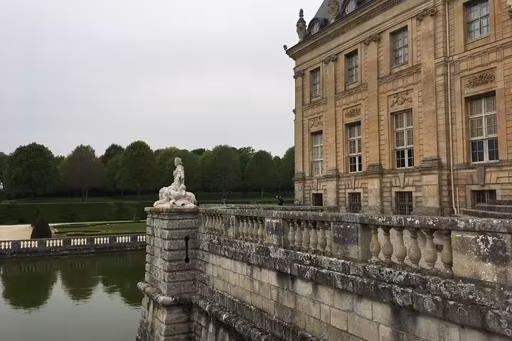 Stone balustrade and white sculpture at Vaux le Vicomte château with formal gardens and moat