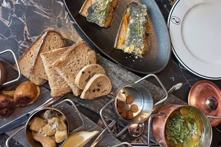 Assorted gourmet vegan dishes including toasted bread and olive tapenade on a marble table, perfect for a food tour.