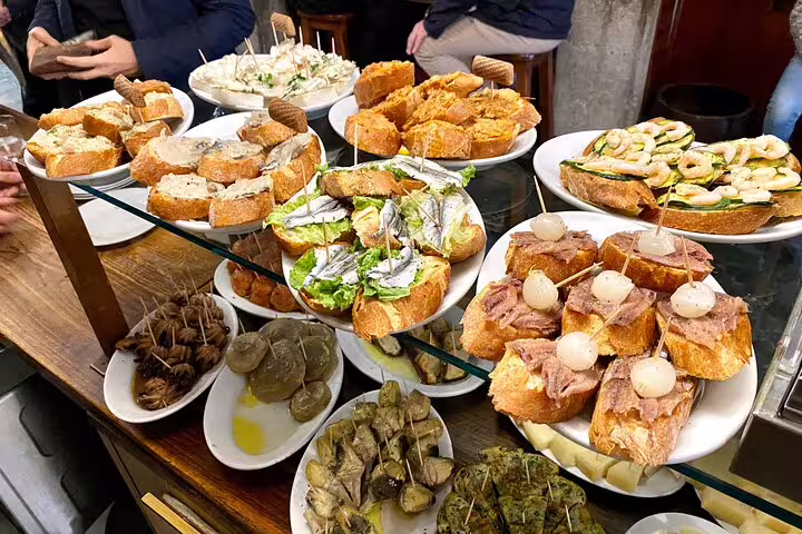 Colorful spread of traditional Venetian cicchetti small bites on plates at a local bacaro during a Venice food tour