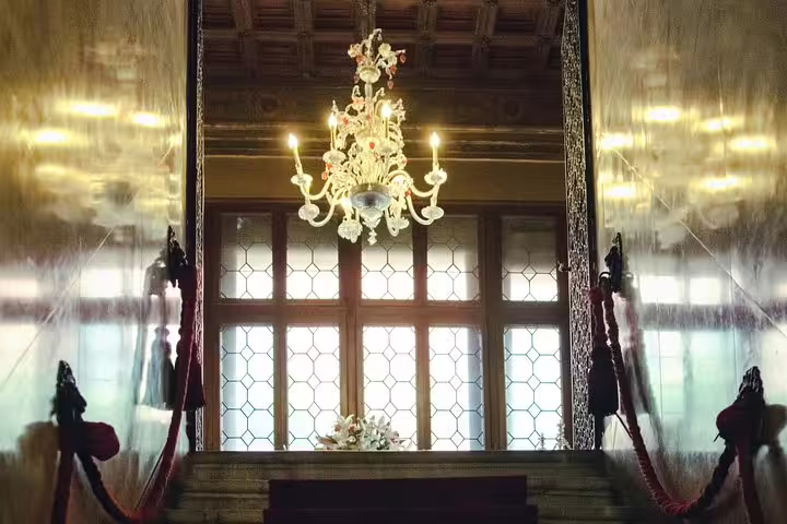 Elegant chandelier lighting a grand staircase in a Venetian palace, enhancing the luxurious ambiance for a special dinner.