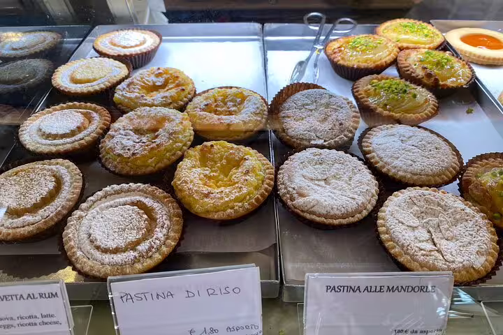 Traditional Venetian pastries including Pastina di Riso and almond tarts dusted with powdered sugar at a Venice bakery