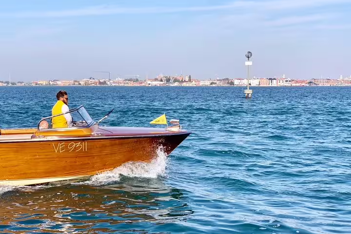 Private Venice airport to hotel transfer by wooden water taxi crossing the lagoon toward Venice city center