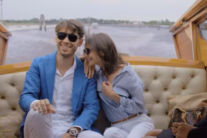 Couple relaxes in a private water taxi, smiling and enjoying the comfortable transfer from Venice Airport to Mestre.