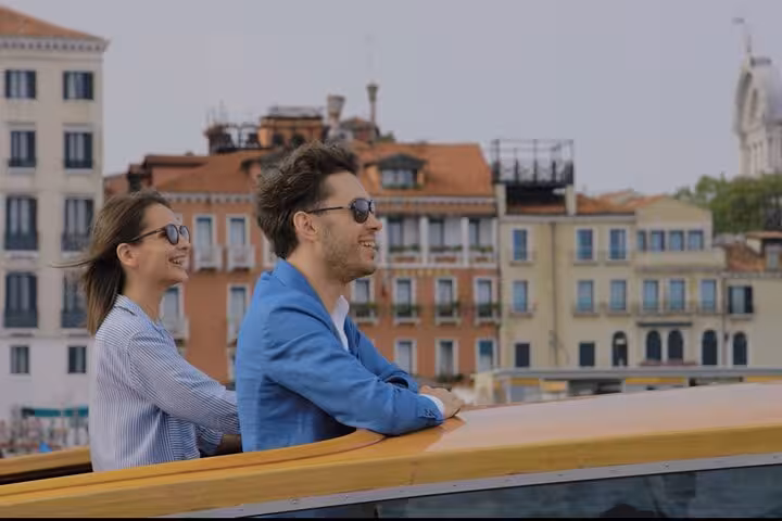 Happy couple enjoys a scenic water taxi ride from Venice Airport to Mestre, surrounded by historic Venetian architecture.