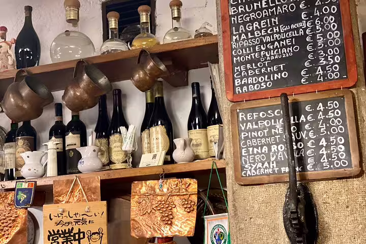 Rustic Venice bacaro wine bar shelf displaying Italian wines with handwritten price menu during a sightseeing food tour