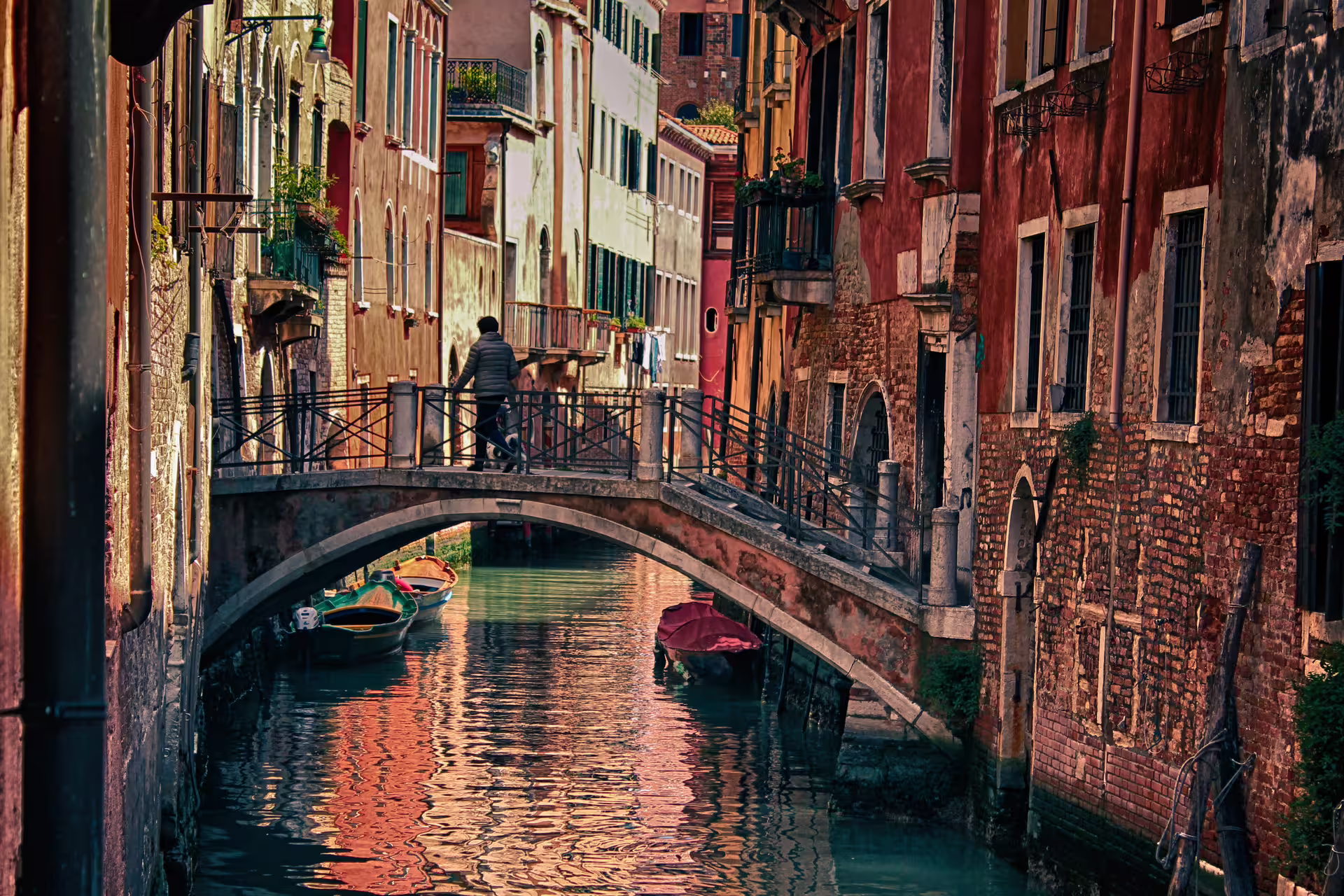 Quiet Venice canal with arched footbridge and moored boats, typical scene on 2-day Venice trip from Rome