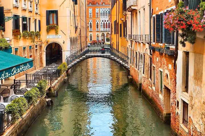 Charming canal in Venice lined with colorful buildings and flowers, perfect for a serene walking tour.