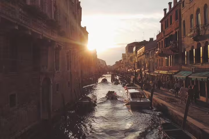 Sunset view of a lesser-known Venice canal with local boats, historic facades and evening life on a private hidden-gems tour