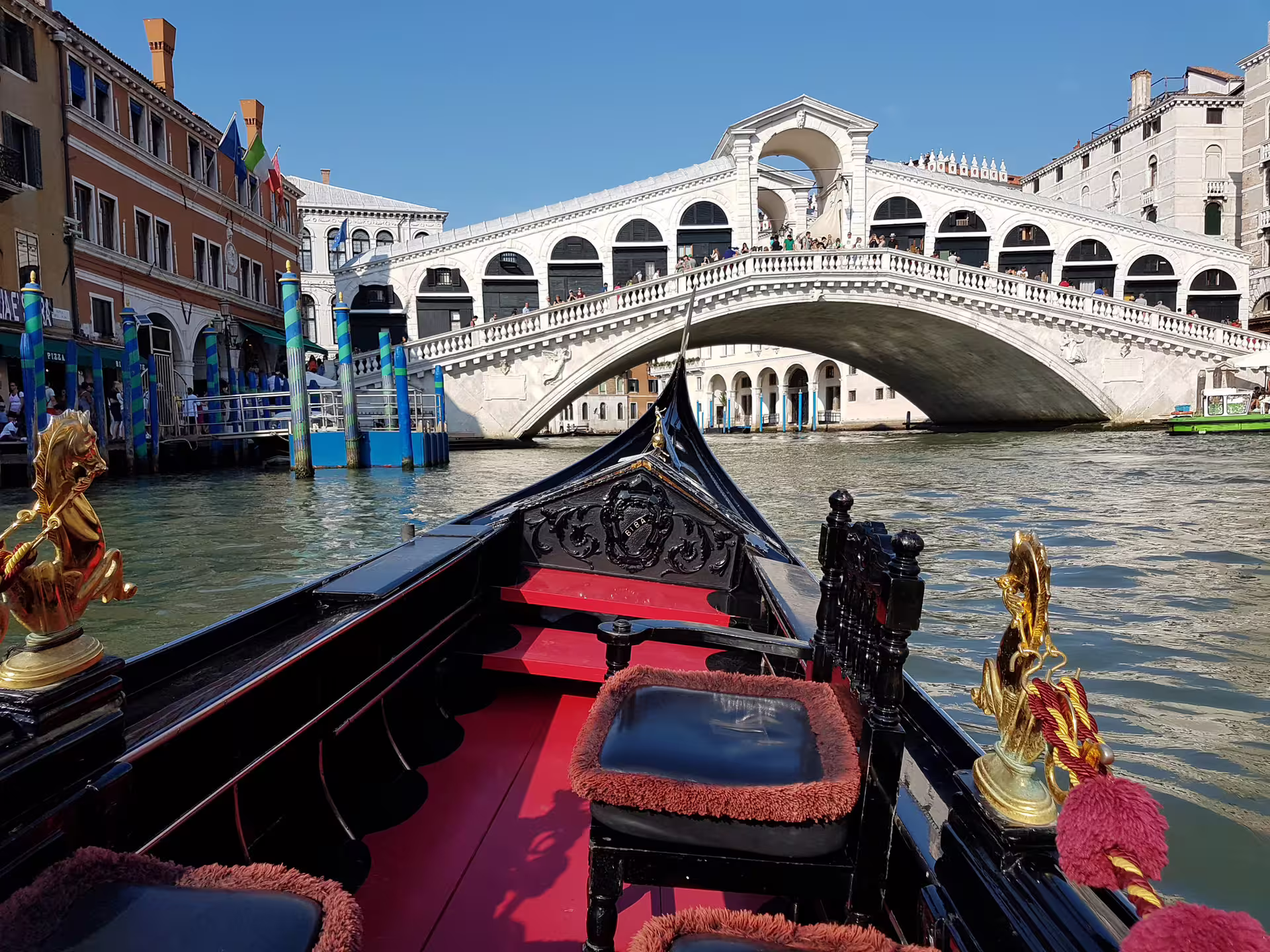 Venice gondola ride on the Grand Canal passing under the historic Rialto Bridge during a guided walking and boat tour