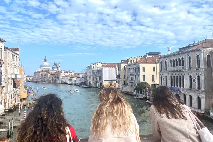 Three tourists admiring the scenic Grand Canal and Santa Maria della Salute on a Venice sightseeing walking tour