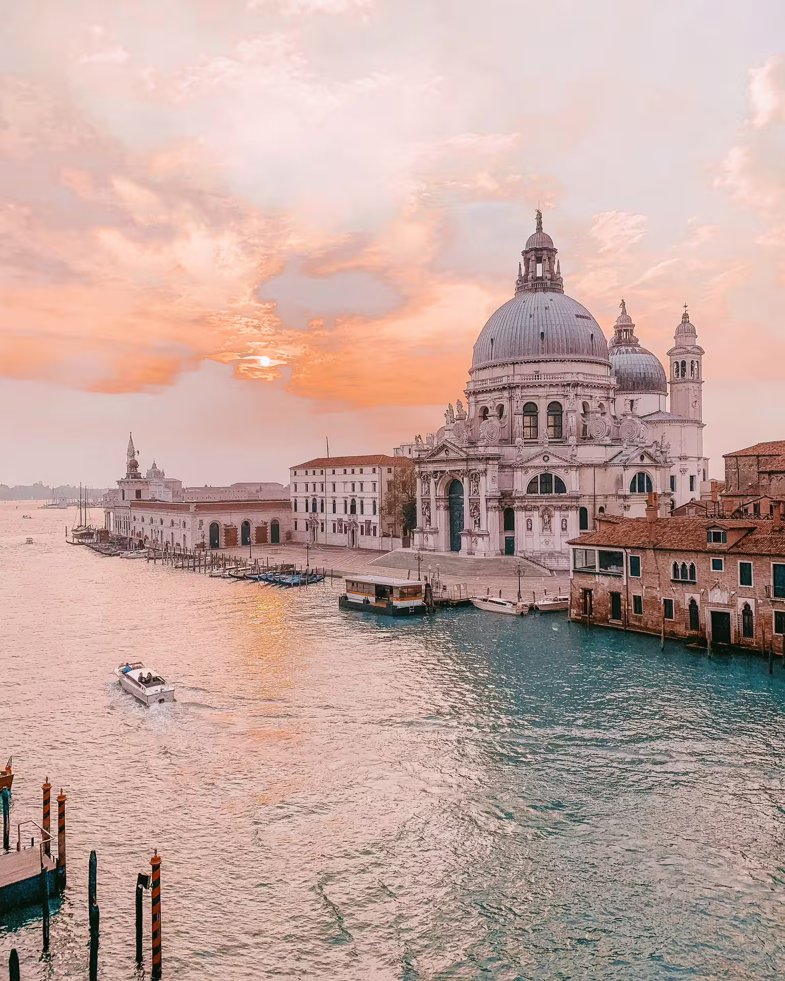 Venice Grand Canal at sunset with a boat passing by, highlighting iconic architecture and serene waterways.